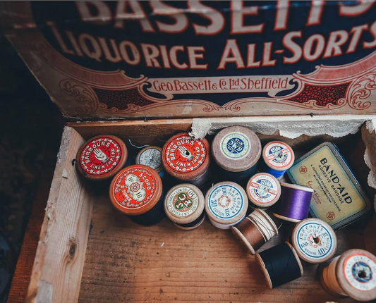 Rustic vintage style image of wooden box with cotton reels inside.