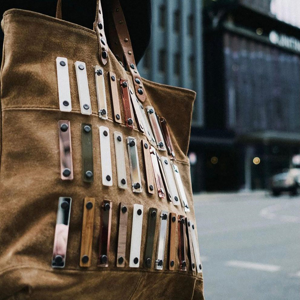 METANoIA tan recycled leather medium handbag with acrylic and wooden vertical accents studded in a repeatitive fashion in an array of natural wooden brown colours, hints of red and copper. 