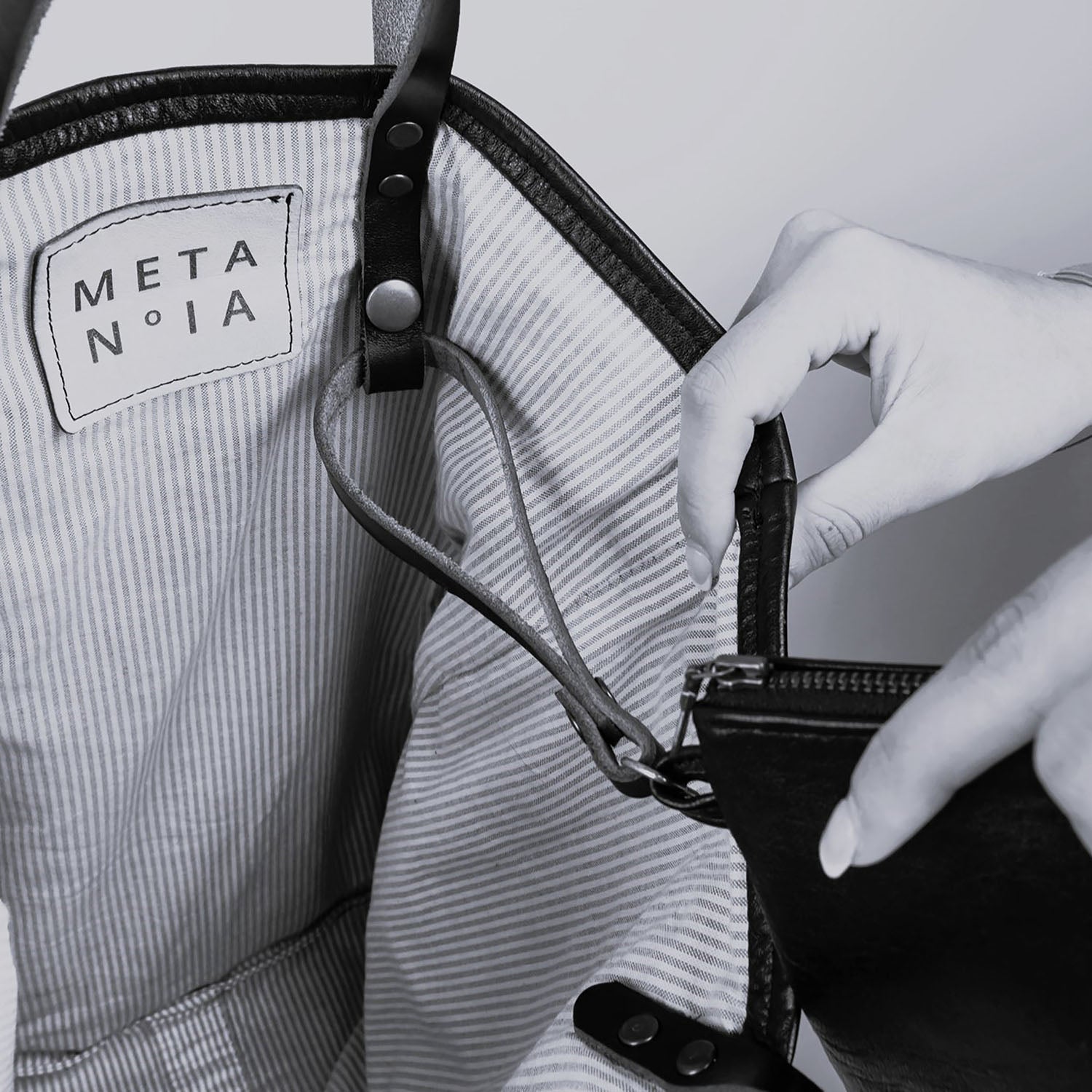 The METANoIA Medium Bag inside featuring pinstripe fabric sourced from recycled fabric and a caramel leather woven label lasered with the iconic METANoIA label.