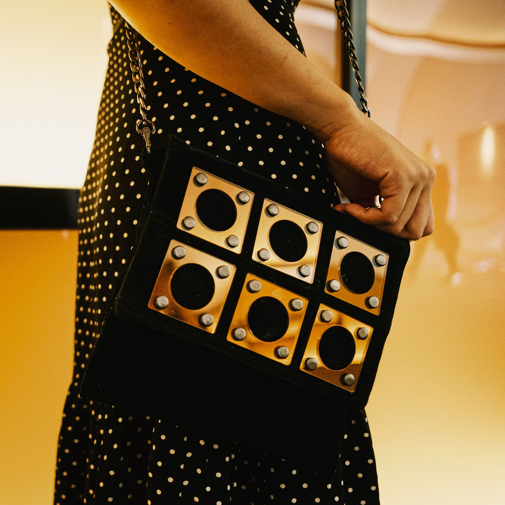 METANoIA black recycled leather small handbag with square and hollowed circle bronze acrylic forms fashioned into a repeative fashion. 